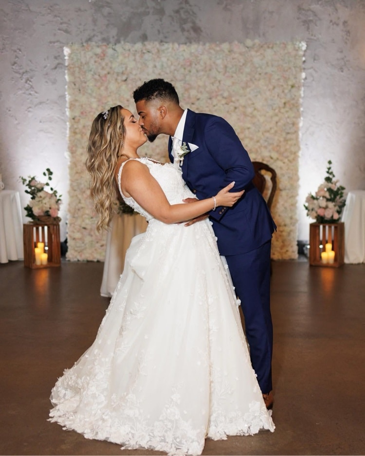 Wedding — couple kissing in front of flower wall
