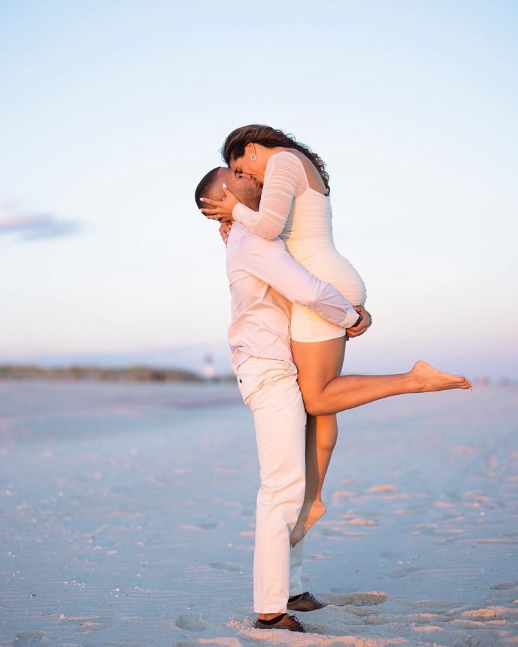 Engagement session — couple lift kiss on the beach at sunset